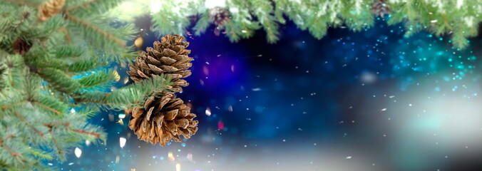 Christmas tree branch with cone on blue blurred festive bokeh confetti snow flakes on background copy space template banner 