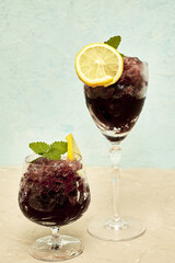 frozen red wine in two glass glasses decorated with a slice of lemon and lemon leaves