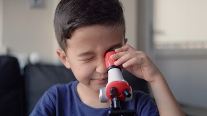 Handsome preschooler studies the microcosm through a microscope