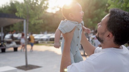Happy father is holding cute baby and kisses while he is laughing