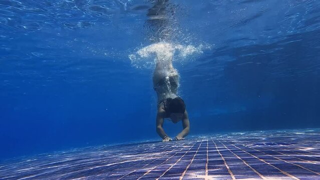 Slow motion video of little girl practice swim and dive underwater in swimming pool at summer vacation