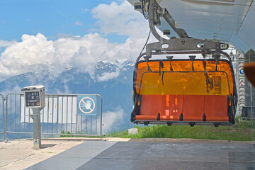 Bright orange chairlift at the station in the mountains. Summer outdoor activities.