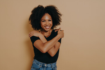 Image of beautiful pleased young dark skinned female with voluminous afro hairstyle