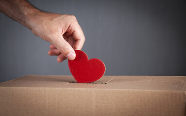 Male hand putting red heart in box.