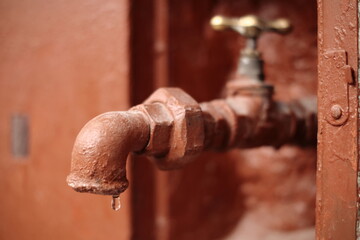Water is dripping from the tap outside the house.
Z kranu na zewnątrz domu kapie woda. - obrazy, fototapety, plakaty