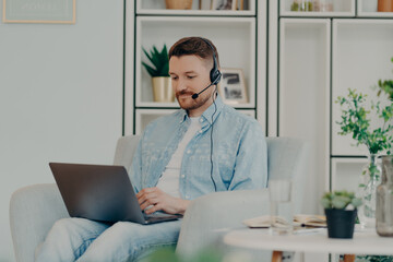 Happy young man sitting and typing on laptop