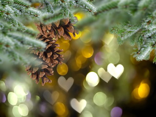 Christmas tree branch with cone and bokeh light heart sumbol gold bakcground template copy space
