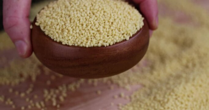 Take a bowl of raw cereal porridge couscous from wheat or millet, cooking dishes from traditional cereals crushed yellow couscous