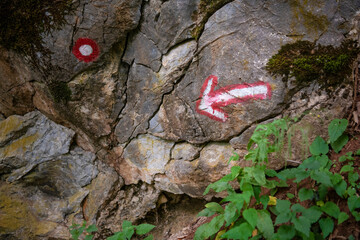 Hiking trail road with red and white arrow and circular mark on a layered Rock in Forest in Djerdap...