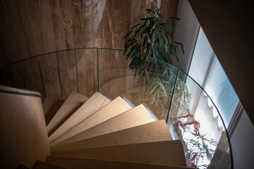 Indoor modern wooden Spiral staircase in bright interior inside spacious residential mansion.

