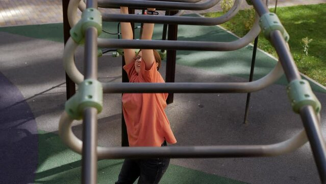 A teenage girl on monkey bars crawls on a children's playground.