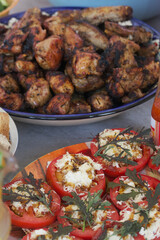 Grilled meat. Lies in a bowl. Vegetables and herbs nearby.