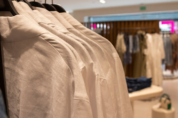 Beige female shirts, on hangers. Defocused store background. Fashion concept.