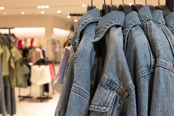Fototapeta na wymiar Female denim jackets on hangers. Defocused store background. Fashion concept.