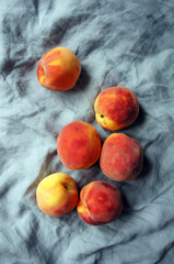 Pile of colorful fresh juicy peaches on blue linen pastel background. 