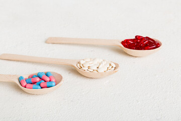 Vitamin capsules in a spoon on a colored background. Pills served as a healthy meal. Red soft gel vitamin supplement capsules on spoon