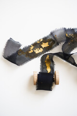 Black transparent silk ribbon with gold elements, close-up on a white background