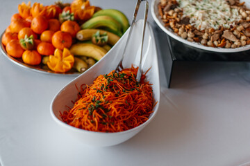 A healthy buffet selection with fresh fruits and carrot salad at an event.