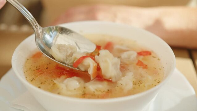 Man eats soup with dumplings at lunch. Central Asian and Caucasian cuisine.
