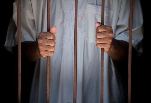 Religious muslim islam man in white session hold steel in jail on black background, concept for prisoner,sadness,detain,erroneousness