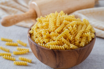 Raw fusilli pasta in wooden bowl.