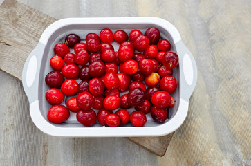 Ripe red cherry plums on plate. Juicy fruit on wooden background, closeup. Fresh plum, vegetarian food