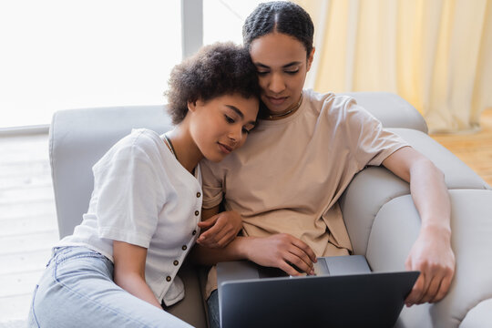 Young african american same sex couple using laptop on couch at home