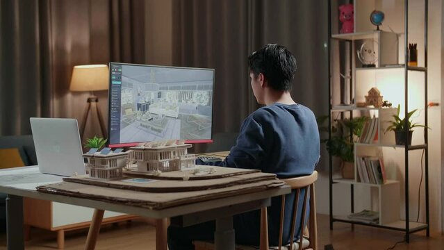 Asian Male Engineer Rotate 3D Room And Putting Colours On Furnitures While Working On A Desktop At Home. Cyber Games House Design And Decoration
