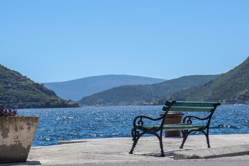 Naklejka na ściany i meble Old vintage empty bench by the sea and beautiful landscape with mountains
