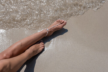 Girl sunbaths on the beach wearing an anklet - 523192354