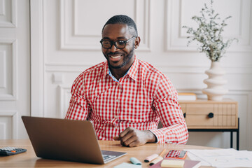 Happy african american man office worker chatting online with business partner via internet