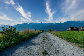 Green field with house and hills and trees