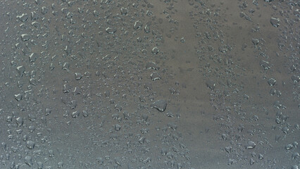 Raindrops on gray metal surface.