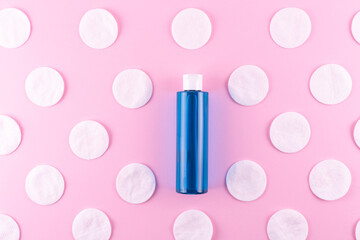 cotton pads, blue bottle with toner or micellar cleansing water on pink background, top view. Beauty, skin, hair or body care concept.selective focus. Liquid beauty product in plastic packaging © Тарас Белецкий