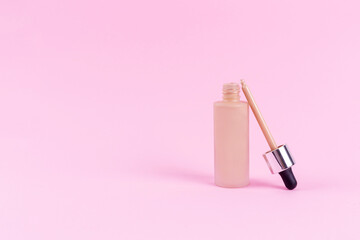 Opened liquid foundation cream with pipette unbranded bottle on a pink background. BB cream for professional make-up, eyedropper for applying to the face. Cosmetic female accessory, fluid. Mock up .