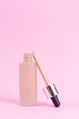 Opened liquid foundation cream with pipette unbranded bottle on a pink background. BB cream for professional make-up, eyedropper for applying to the face. Cosmetic female accessory, fluid. Mock up .