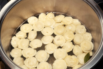 Meat dumplings are boiled in a pot of boiling water.