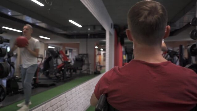Wheelchair athlete and his trainer working out with a medicine ball
