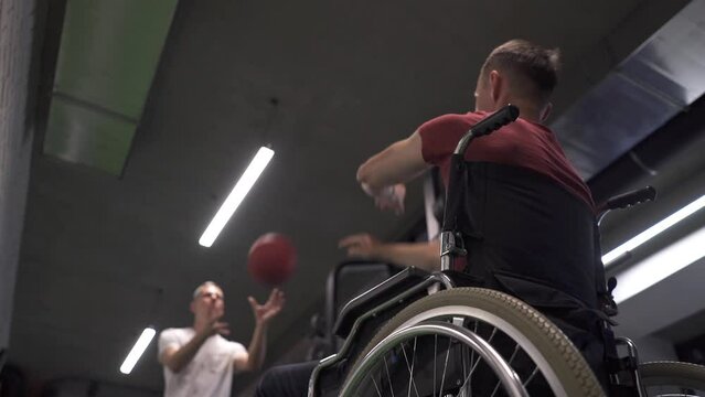 Wheelchair athlete and his trainer working out with a medicine ball