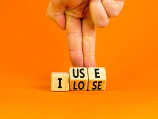 I use or lose it symbol. Concept words I use and I lose on wooden cubes. Businessman hand. Beautiful orange table orange background. Business and i use or lose it concept. Copy space.