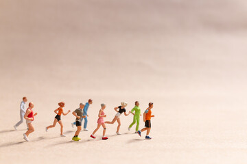 Fototapeta na wymiar Miniature People exercising while running in a group on the beach. Living an active lifestyle concept