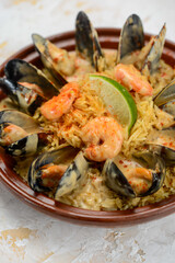 pilaf with mussels and greens in a clay plate on a white background, vertical photo
