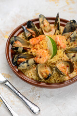 pilaf with mussels and greens in a clay plate on a white background, vertical photo
