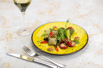 stuffed tomatoes and eggplants in a yellow plate on white with a glass of wine
