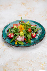 fresh salad with tomatoes, spinach and radish in a blue plate on a white background
