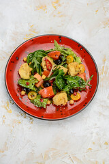 fresh salad with chicken and tomatoes in a red plate on a white background

