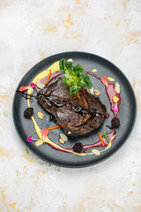 a large grilled meat steak in a black plate
