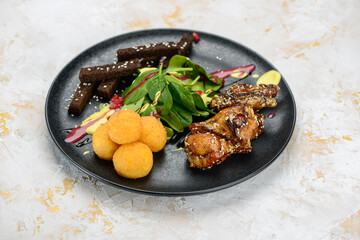 chicken wings with spinach and crackers in a black plate on a white background
