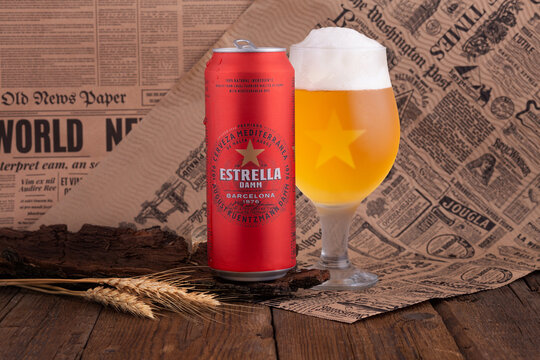 POLTAVA, UKRAINE - August 13, 2022: Estrella Damm beer on wooden background. Estrella Damm is a pilsner beer, brewed in Barcelona.
