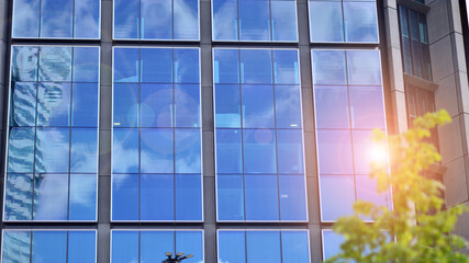  Modern glass facade against blue sky. Bottom view of a  building in the business district. Low angle view of the glass facade of an office building.